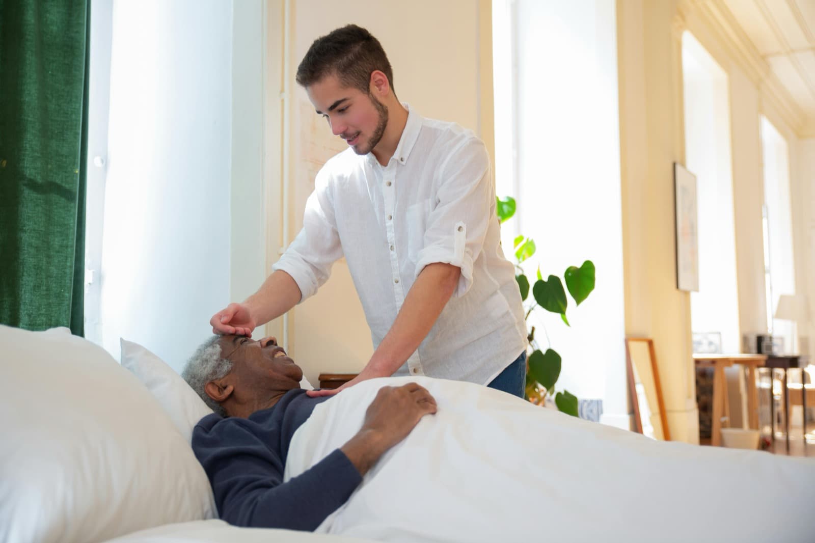 A caregiver offering gentle, person-centered support to a client in bed